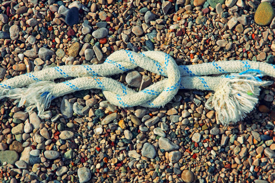 Straight sea knot on smal vivid pebble background.