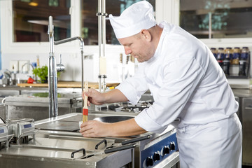 Chef using brush to prepare a dish in the kitchen