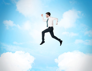 Fototapeta na wymiar Business person jumping over clouds in the sky