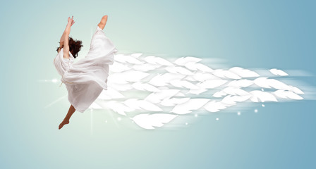 Naklejka premium Healthy young woman jumping with feathers around her