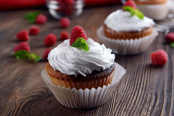 Delicious cupcakes with berries and fresh mint on wooden table close up