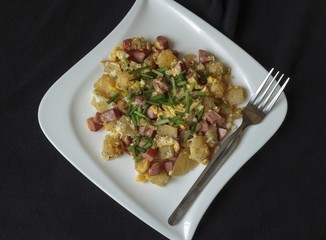 scrambled eggs served with pieces of sausage on a white plate detail