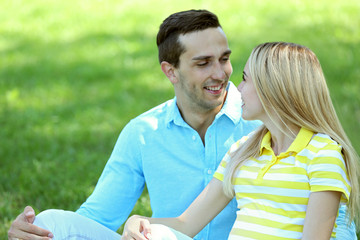 Obraz premium Young pregnant woman with husband sitting on green grass in park