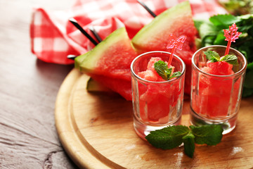 Cold watermelon desserts and drinks in glasses, on wooden table background