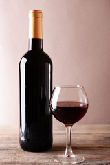 A bottle of red wine and a glass on wooden table