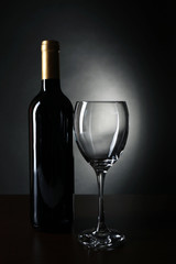 Bottle of wine and empty wine glass on dark background