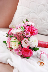 Wedding bouquet and bridesmaid dress on sofa in room