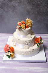 Obraz na płótnie Canvas White wedding cake decorated with flowers on grey background