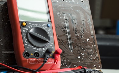 Red multimeter on motherboard background