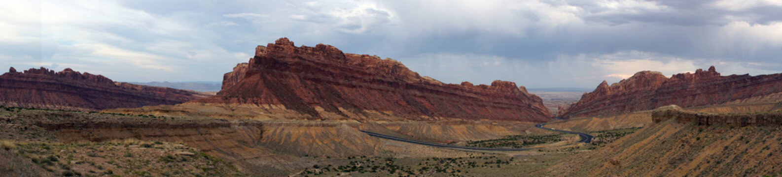 Panoramic of Road winds through Spotted Wolf Canyon with dramati