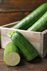 Fresh zucchini in box on wooden background