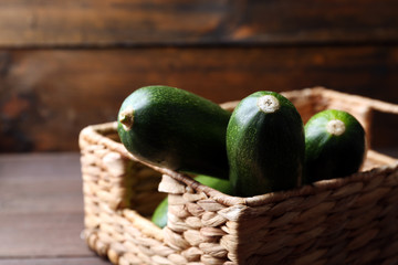 Fresh zucchini in wicker basket on wooden background