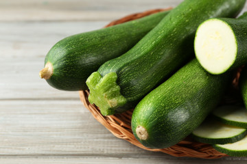 Fresh zucchini on wicker mat on wooden background