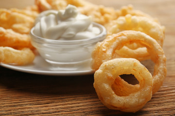Chips rings with white sauce on plate on wooden background