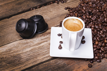 Cup of coffee and pods on wooden table