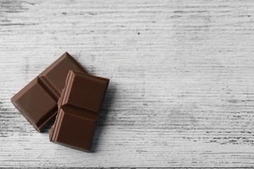 Black chocolate pieces on color wooden background