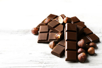 Chocolate pieces with nuts on color wooden background