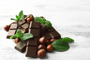 Chocolate pieces with nuts on color wooden background