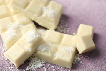 White chocolate pieces and coconut shavings on color wooden background