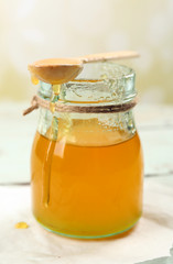 Honey jar with wooden spoon on light background