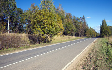 Fototapeta na wymiar Golden Autumn. Suburban shosse with new road markings on cloudless sunny autumn day