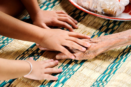 Young hand touches and holds an old woman hands