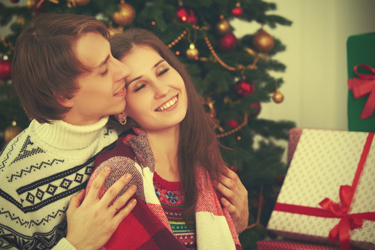 happy tender loving couple in embrace warmed at Christmas tree