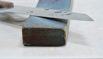 kitchen knife and grindstone on tile floor