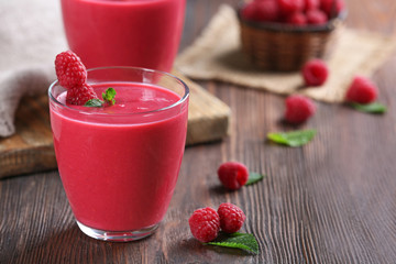 Glasses of raspberry milk shake with berries on wooden table close up