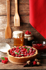 Tart with fresh raspberries, on wooden background