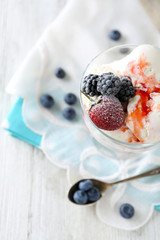 Delicious ice cream with fresh frozen berries and sauce, on color wooden background
