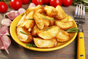 Baked potato wedges on wooden table, closeup