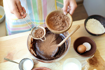 Woman preparing dough for chocolate pie on table close up