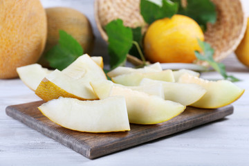 Slices of ripe melons with green leaves on table close up