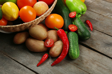 Heap of fresh fruits and vegetables in basket on wooden table close up