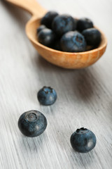 Fresh blueberries in spoon on wooden table close up