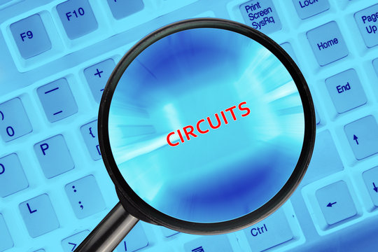 Magnifying glass on computer keyboard with "Circuits" word.