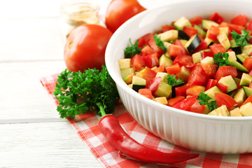 Ratatouille before cooking and ingredients, on wooden background