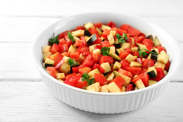Ratatouille, stewed vegetable dish with tomatoes, zucchini, eggplant before cooking, on wooden background
