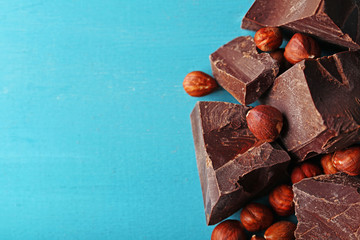 Black chocolate pieces with nuts on color wooden background