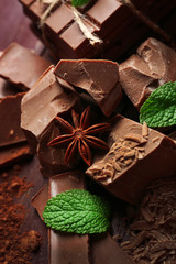 Variety of chocolate pieces, coffee grains and cocoa powder on wooden background