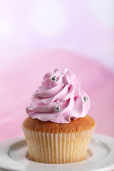 Tasty cupcake on stand, on light background