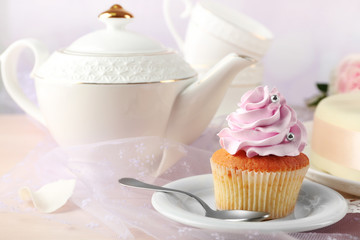 Tasty cupcake on saucer, on light background