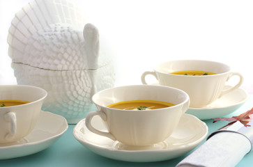 Traditional Thanksgiving pumpkin soup on pale blue table.