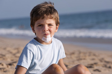 Child, with a wound on the chin, on the beach