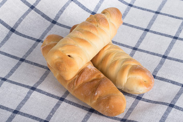 Fresh baked sausages buns on checkered tablecloth like backgroun