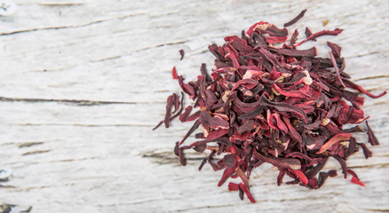 Dried red hibiscus tea leaves over wooden background