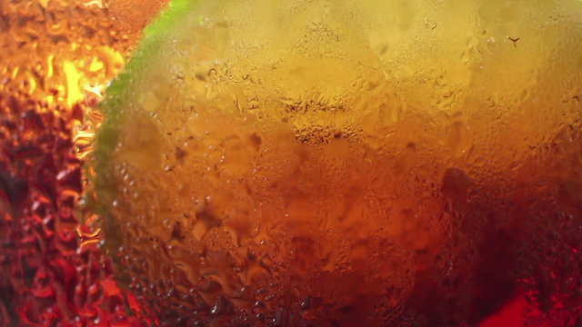 Macro ECU of a slice of lime resting amongst bubbles in a color-colored fizzy
