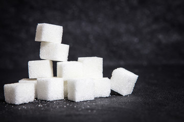 cloose up white sugar cubes on black stone plate background
