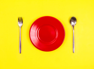 top view of empty red dish with spoon and fork 